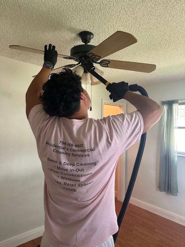 A Mita team member carefully cleaning a ceiling fan